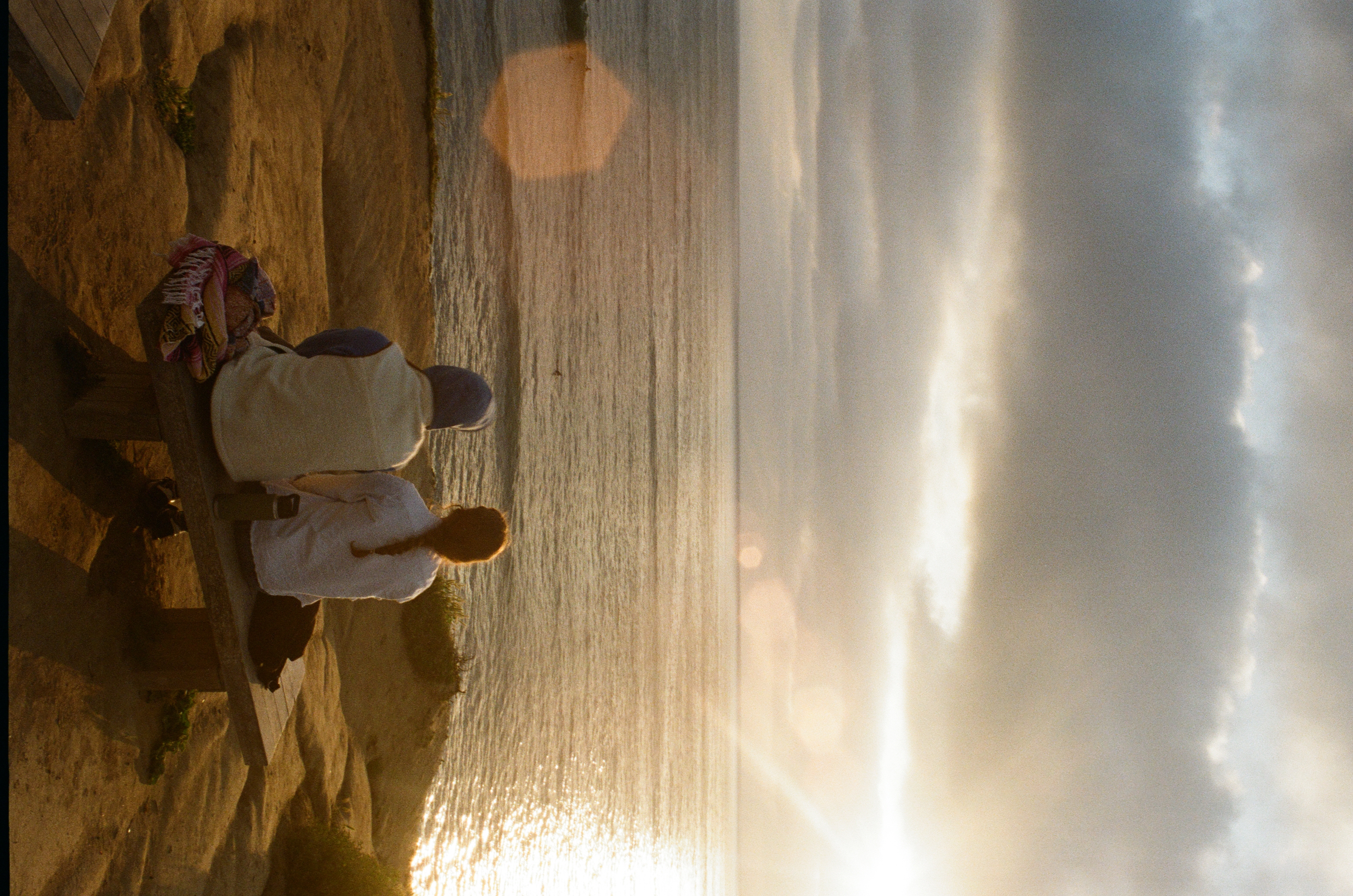 Two friends sitting on a bench at Sunset Cliffs watching the sun go down