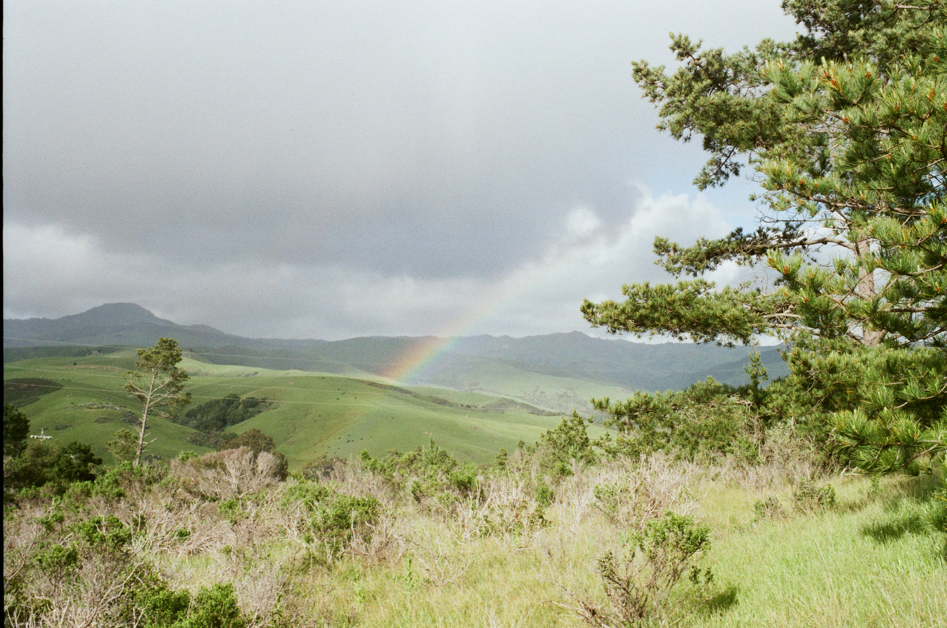 Rolling green hills with a rainbow in the misty distance