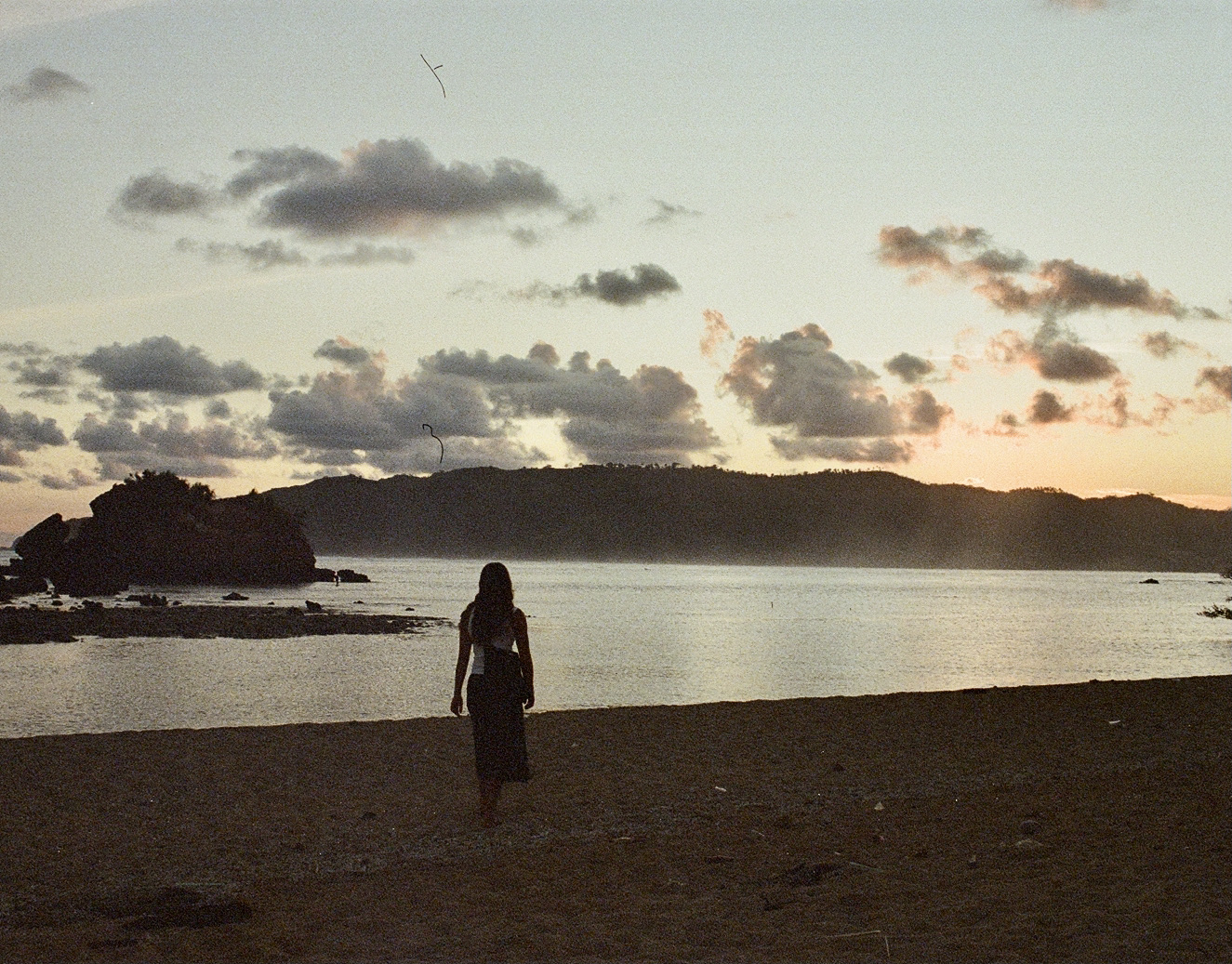 Woman silhouetted at sunset on a tropical beach