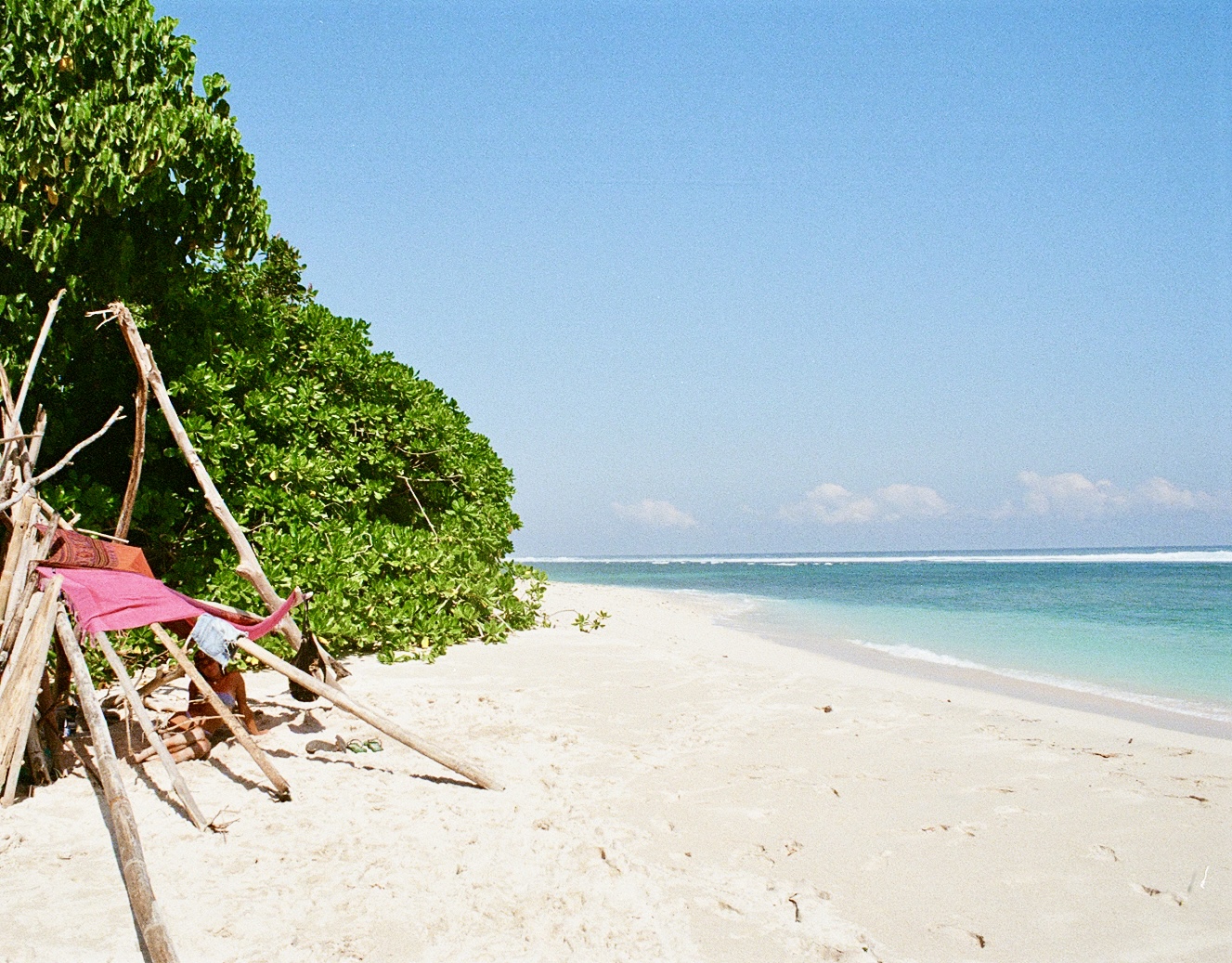 White sand beach with driftwood shelter and turquoise surf, Indonesia