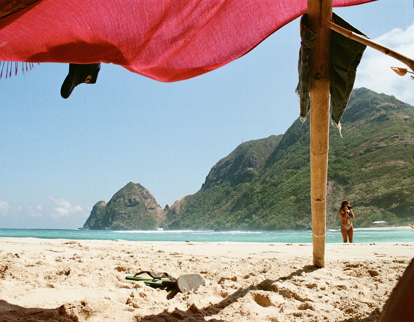 Under a bamboo shade canopy looking out to dramatic cliffs and turquoise sea