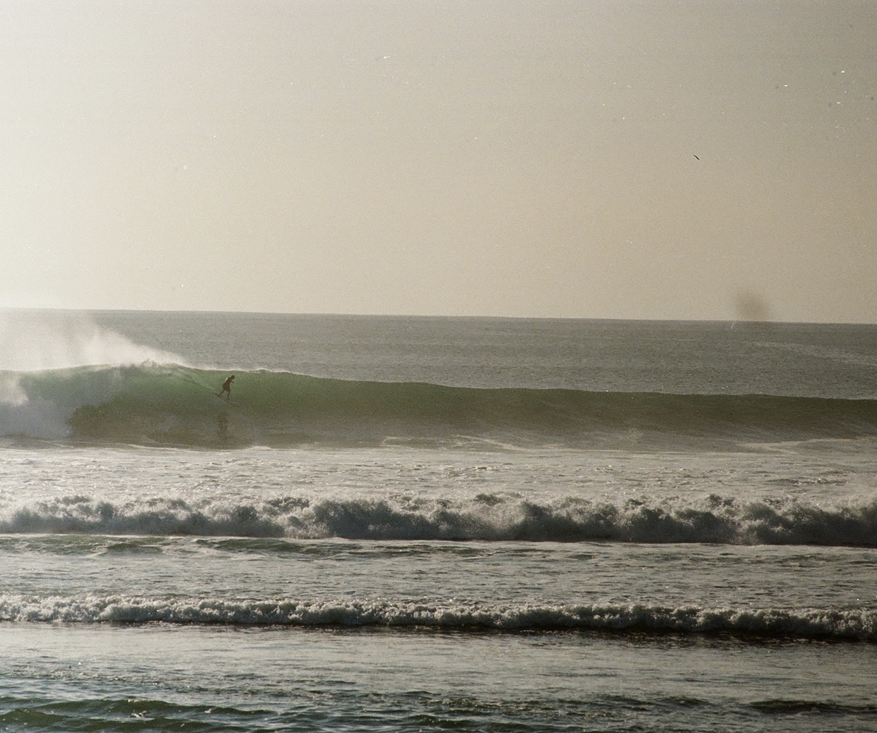 Surfer on a long green wave in Indonesia, film photography