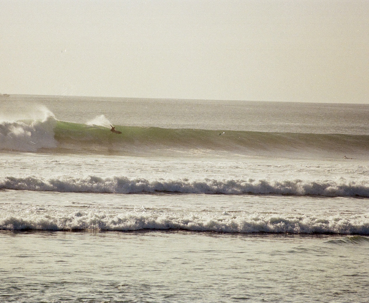 Surfer riding a long green wave in Indonesia, film photography