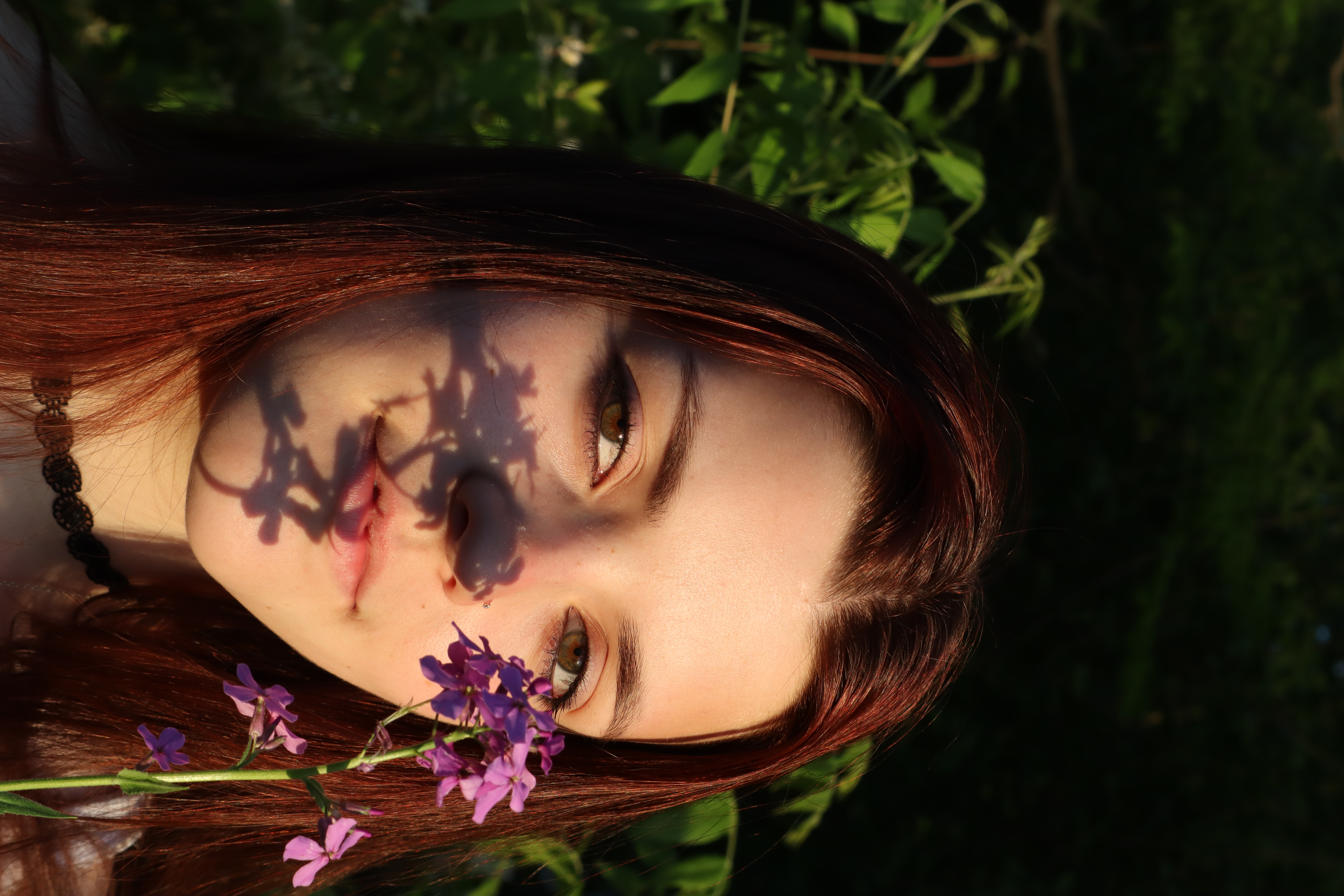 Cassie with flower shadow on her face, golden light in the leaves