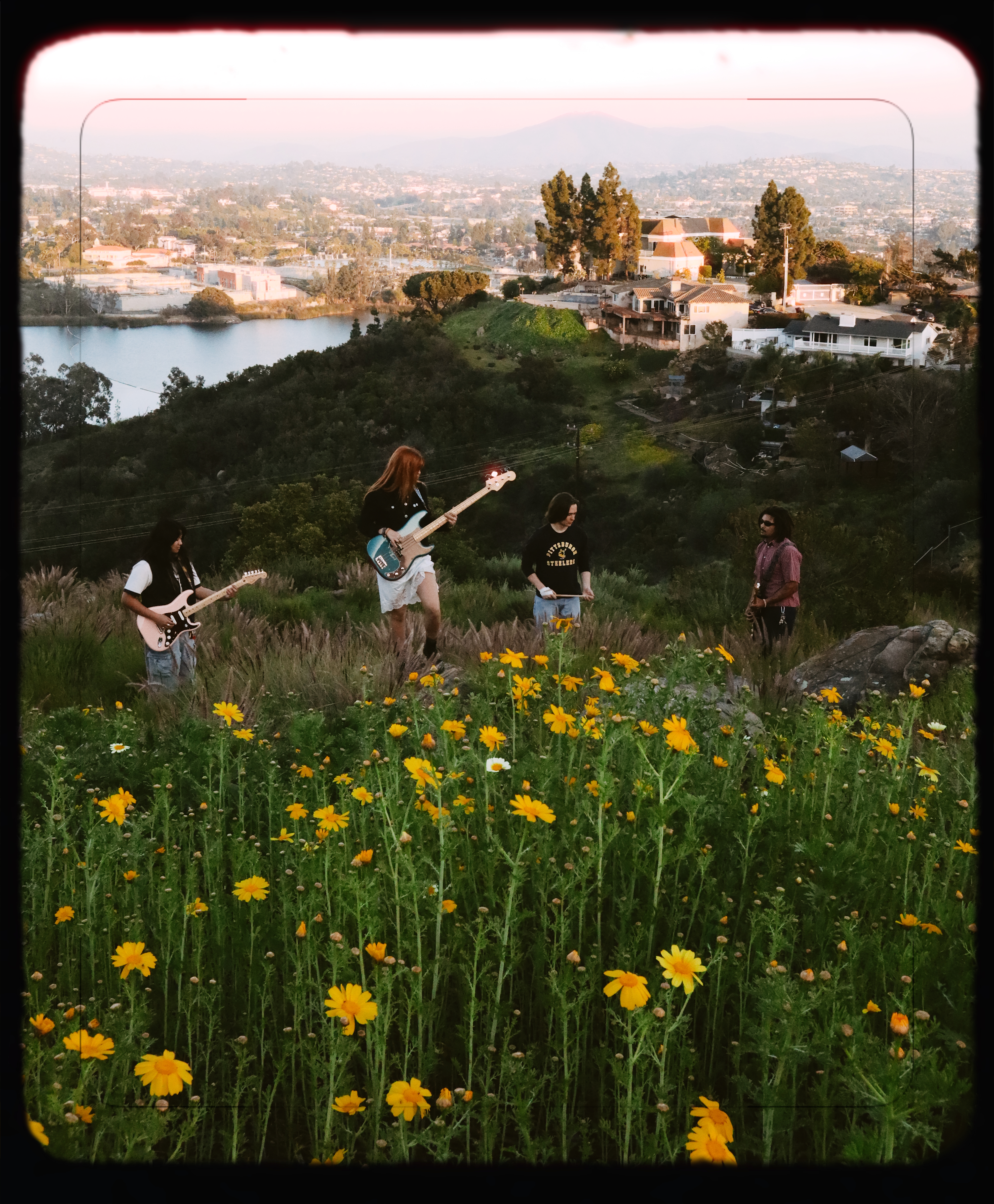 Misfire band on a hillside with yellow wildflowers and city view