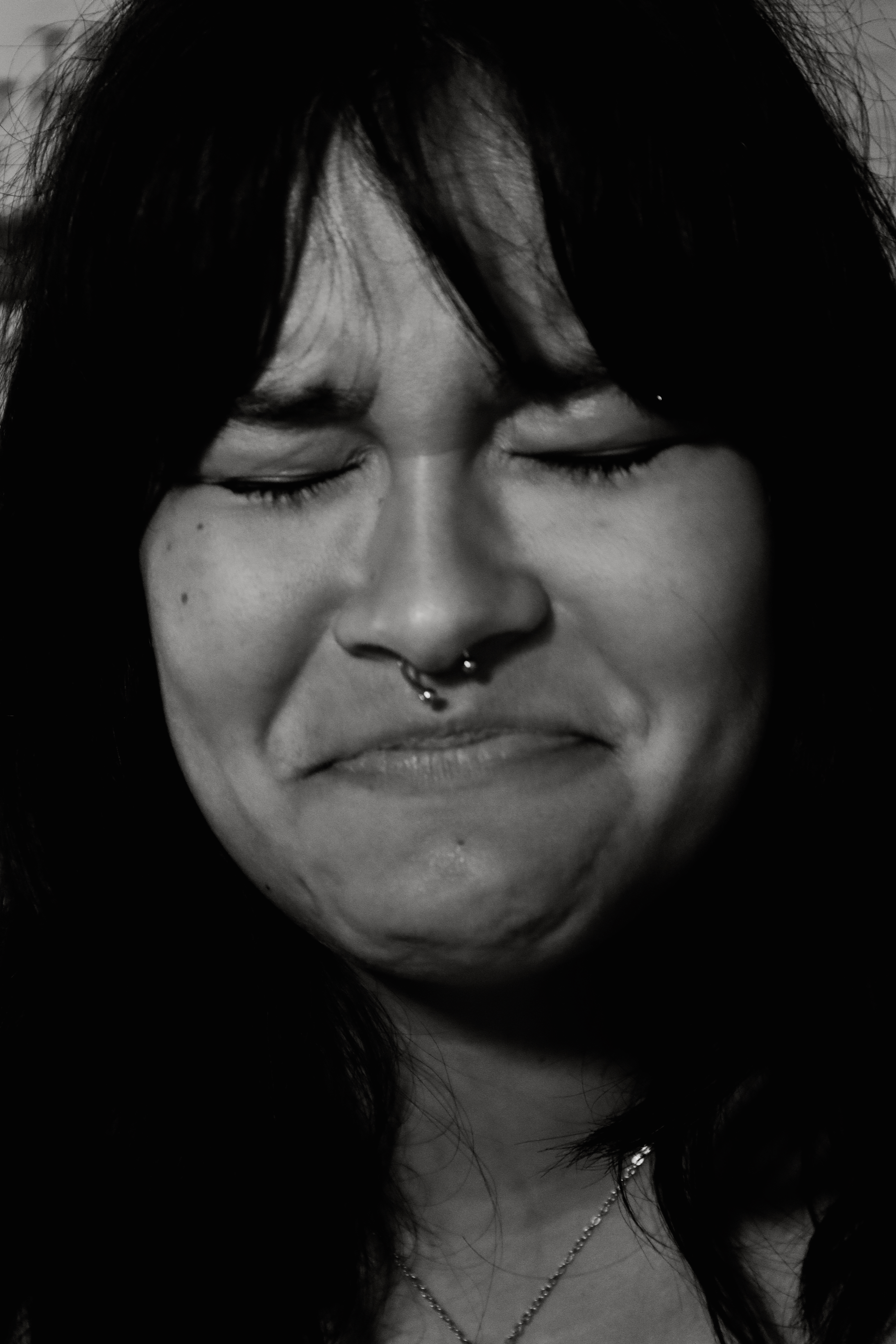 Woman with eyes closed, pained expression, black and white