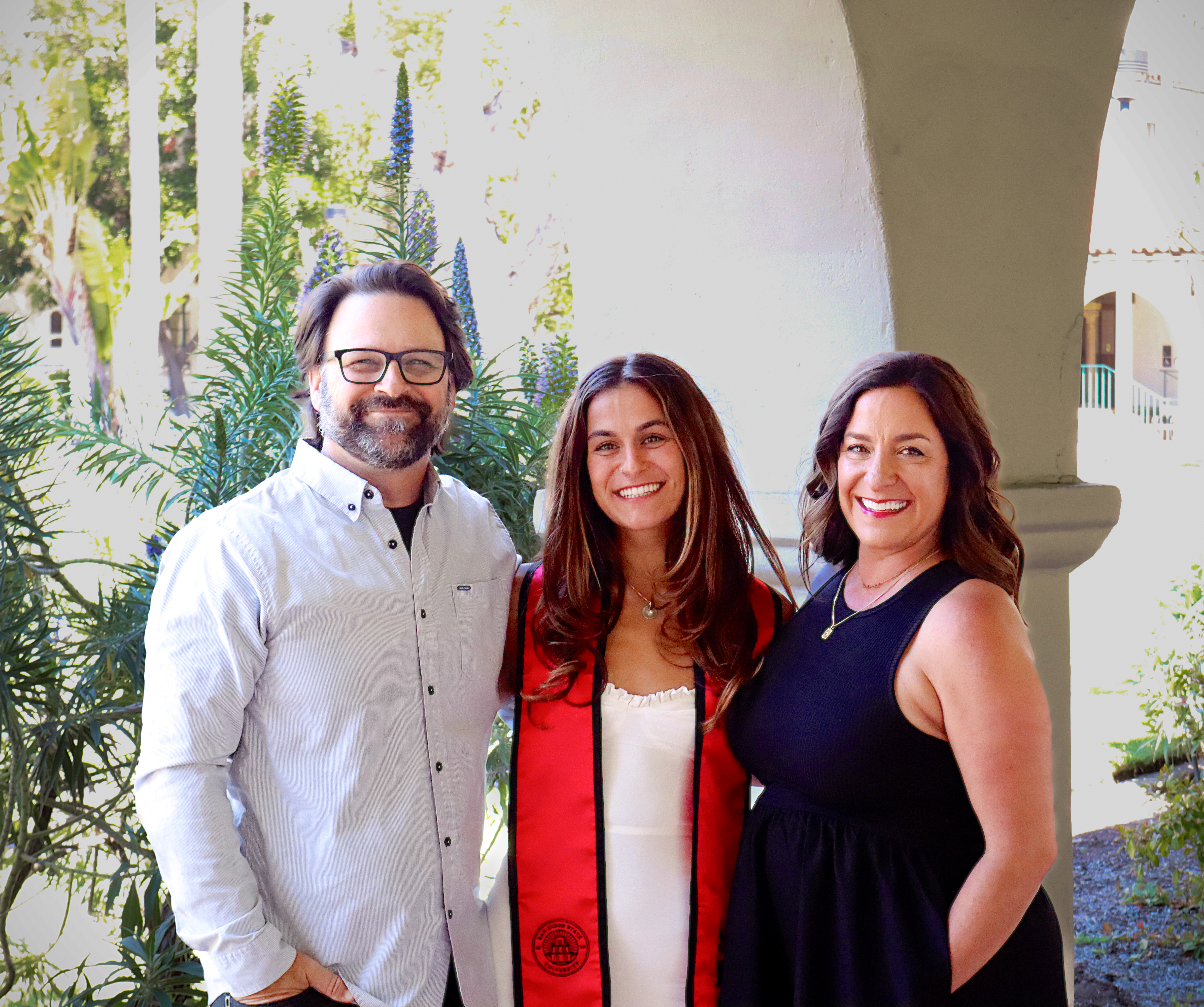 Kayden with her parents smiling in front of the SDSU campus arches