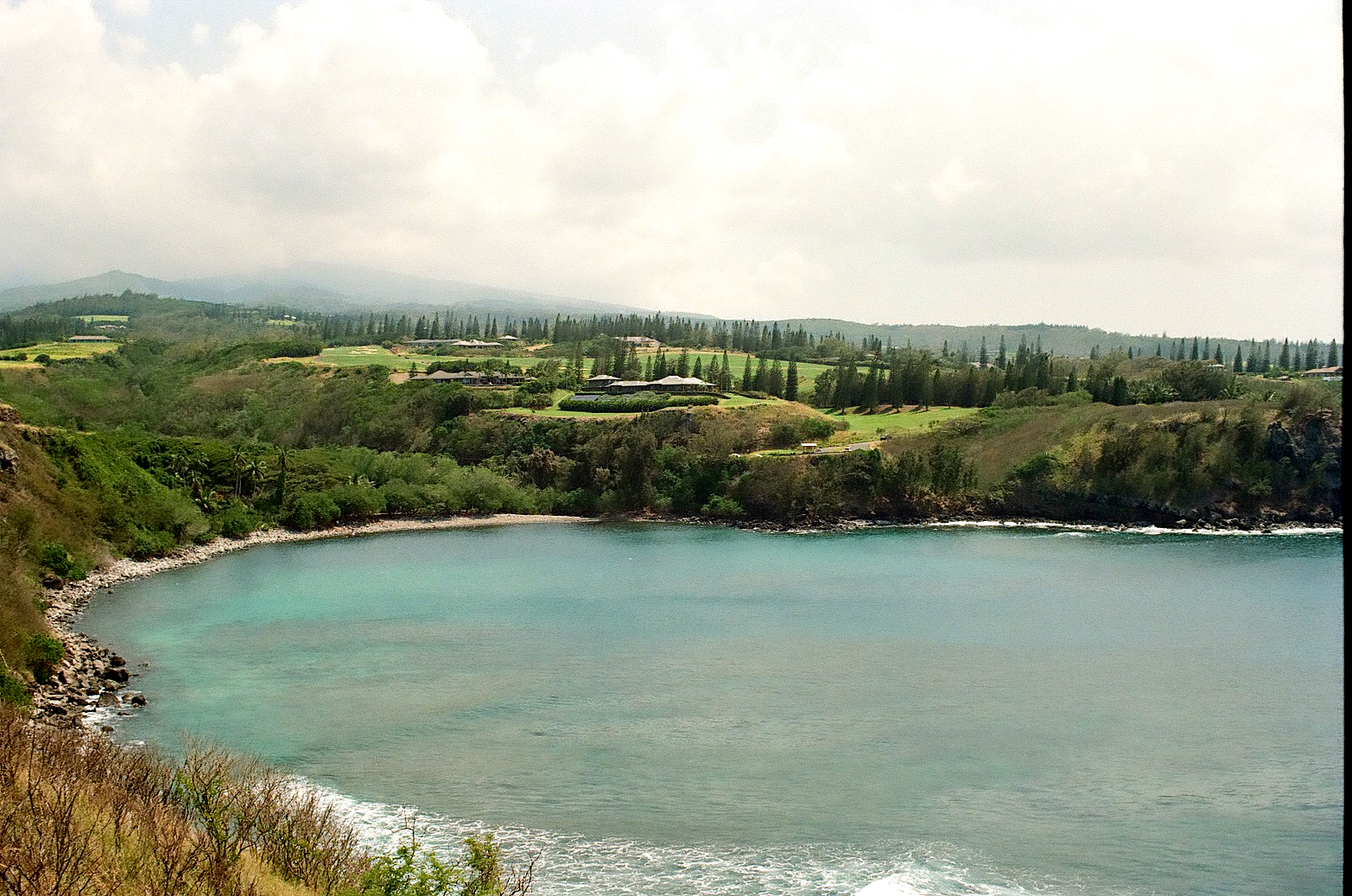 Aerial view of a turquoise Hawaiian bay with green hills behind