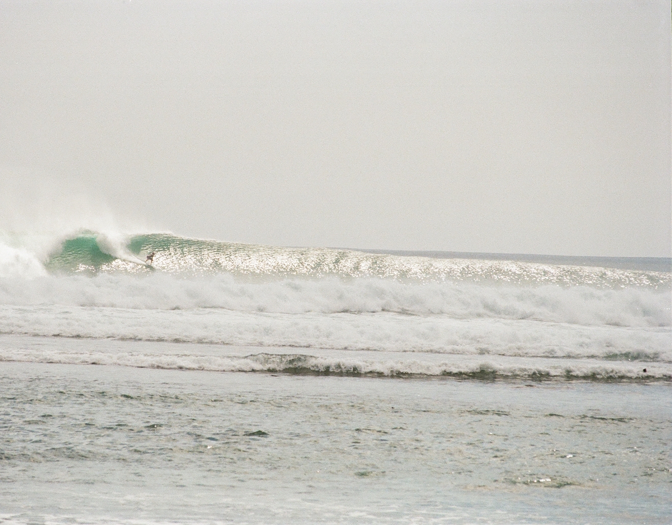 Surfer pulling into a barrel on a long glassy wave