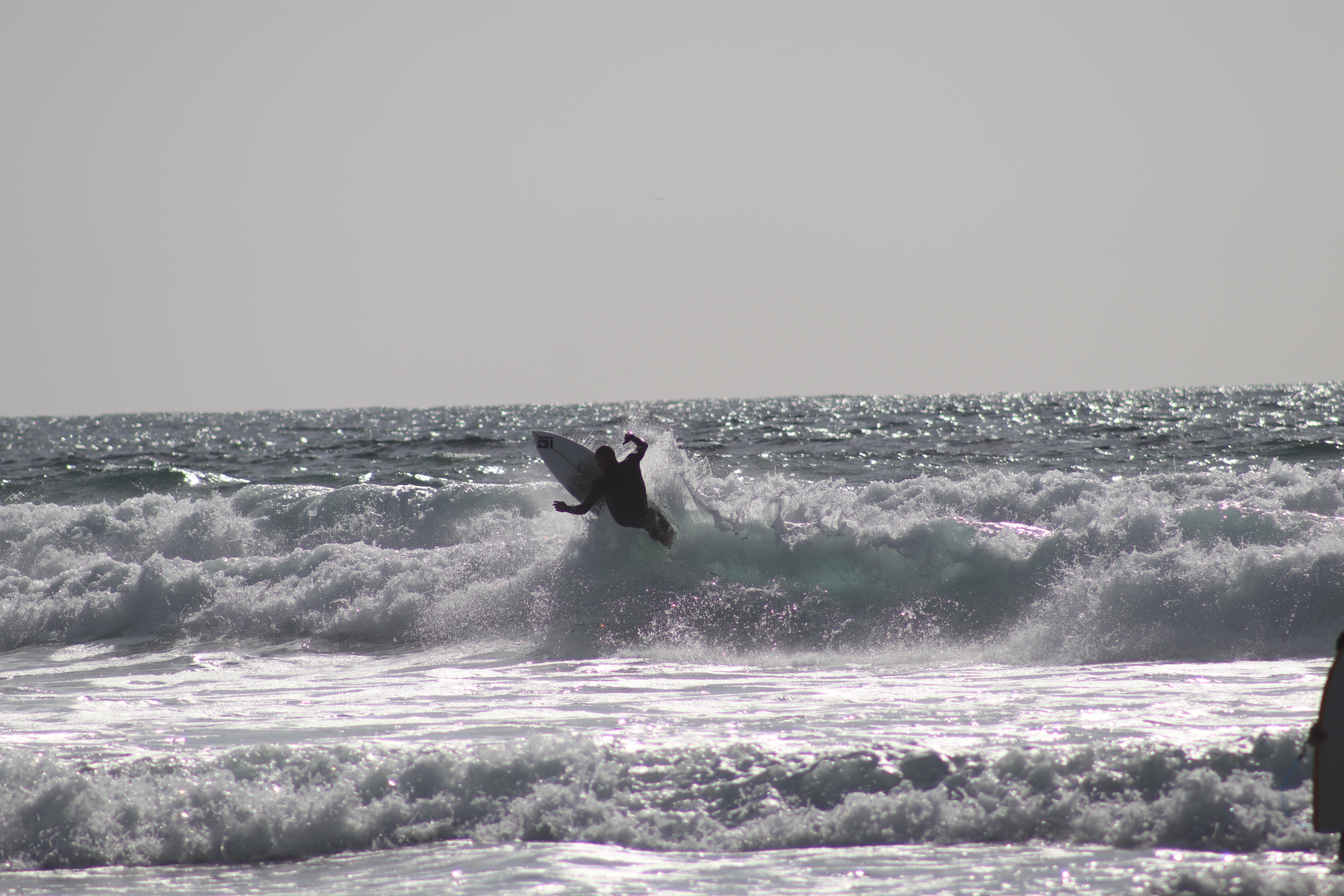 Surfer launching off the lip in silhouette, dramatic spray